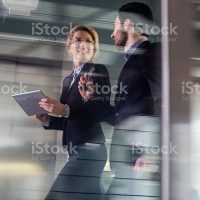 Business professionals having a conversation while passing through office building lobby.